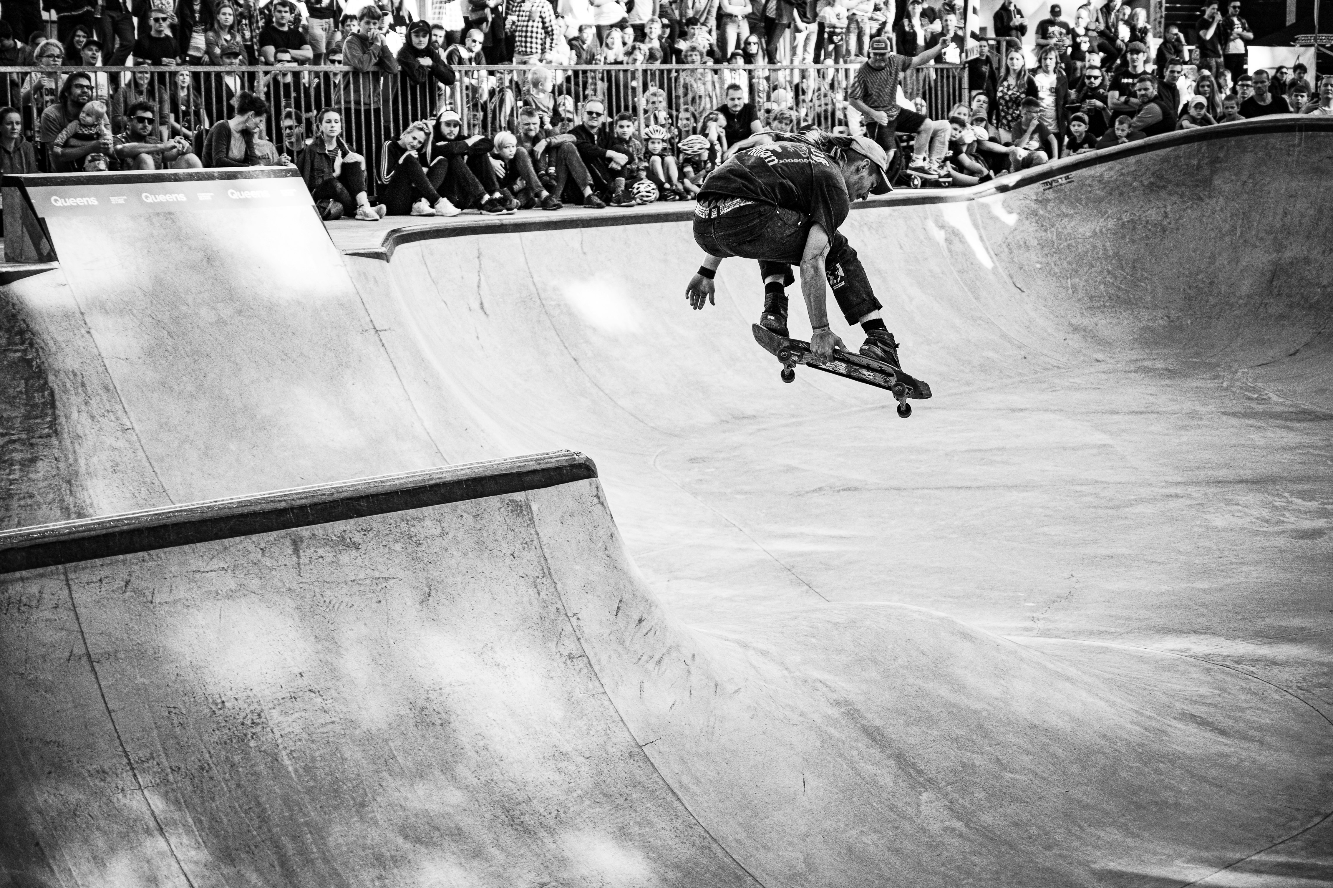 grayscale photo of man riding skateboard doing tricks